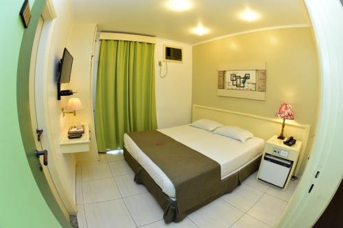 ein Schlafzimmer mit einem Bett und einem grünen Vorhang in der Unterkunft Trade Garden Hotel in Araras