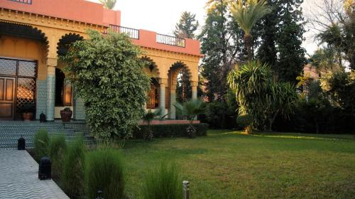 a large house with a lawn in front of it at The Red House in Marrakesh