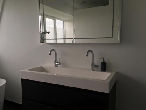 a bathroom sink with two faucets and a mirror at Slaapplaatsen 2-4 personen voor bezoek DTRH of Goffertconcert Bruce Springsteen-Rammstein in Beuningen