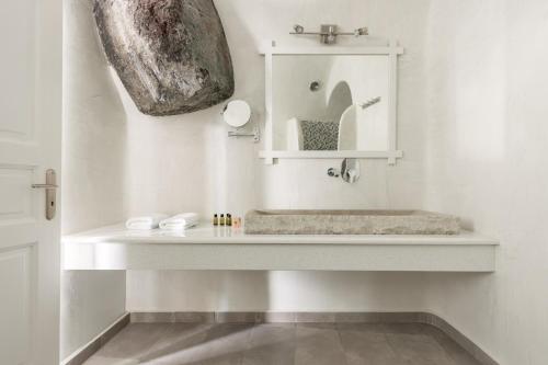 a white bathroom with a sink and a mirror at Vallas Apartments & Villas in Firostefani