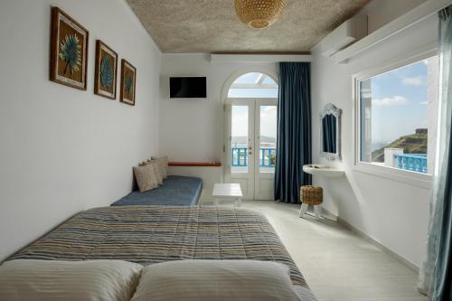 a bedroom with a bed and a large window at Vallas Apartments & Villas in Firostefani