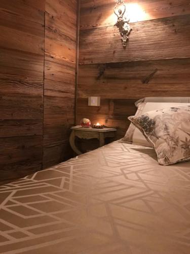 a bedroom with a bed with a wooden wall at LE LANTERNE in Villa dʼAlmè