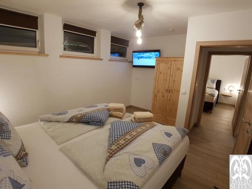two beds in a room with a tv on the wall at DAVID SUITEN in Mauterndorf