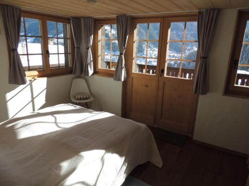 um quarto com uma cama num quarto com janelas em Pradamont 09 em Grimentz