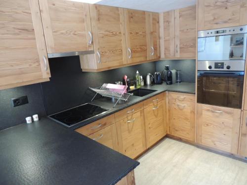 uma cozinha com armários de madeira e um balcão preto em Pradamont 09 em Grimentz