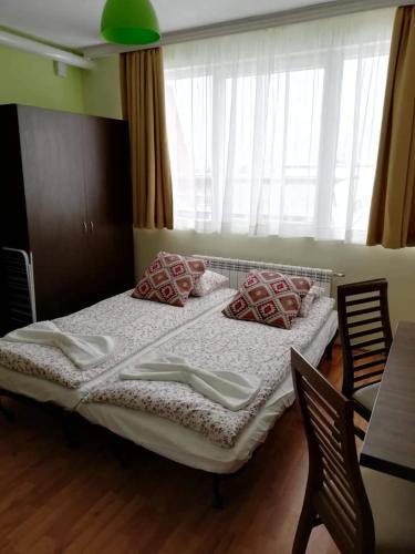 a bedroom with a bed with two chairs and a window at Borovets Apartments, Iglika 2 in Borovets