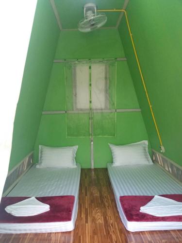 two beds in a green room with a window at ฺBankunyaiy Resort in Ko Yao Yai