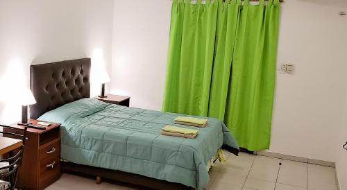 een slaapkamer met een groen gordijn en een bed met twee handdoeken bij Edificio Huayra in La Rioja