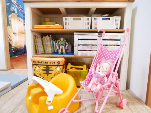 a doll sitting in a chair in front of a shelf at 子供部屋のある一棟貸切り 奄宿り Amayadori in Amami
