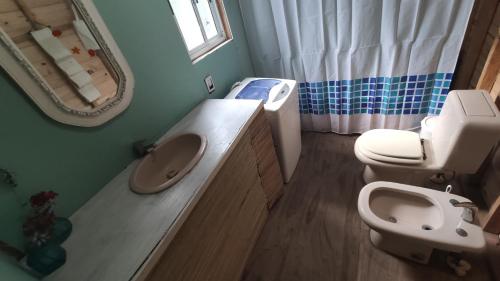 een badkamer met een wastafel, een toilet en een spiegel bij Verdemar in La Paloma
