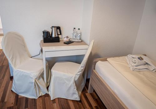 a room with two beds, a desk and a chair at Hotel Bouzid - Laatzen in Hannover