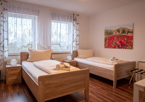 Hotel Bouzid - Laatzen في هانوفر: سريرين في غرفة بها نافذتين