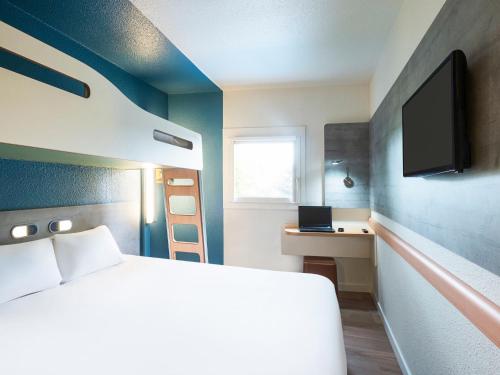 a bedroom with a bed and a desk with a laptop at Ibis Budget Le Havre Les Docks in Le Havre