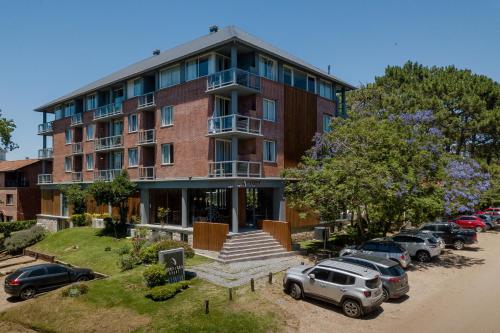 a large brick building with cars parked in a parking lot at Destinar Apart in Carilo