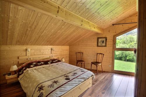 een slaapkamer in een blokhut met een bed en 2 stoelen bij CHALET WIFI - LE BIOT - 8 PERSONNES - CHALET MORAND in Le Biot