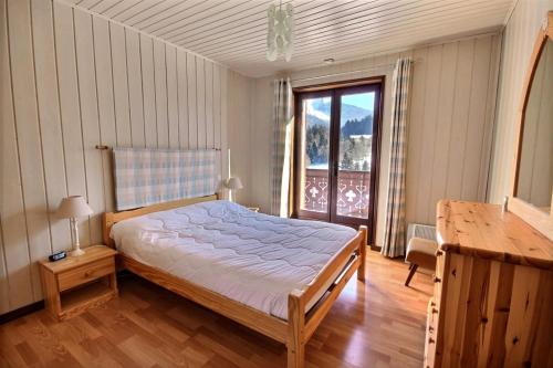 a bedroom with a bed and a large window at CHALET AVEC VUE DEGAGEE - SAINT JEAN D'AULPS - 8 PERSONNES - MOUILLETTES in Saint-Jean-d'Aulps