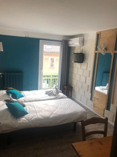 a bedroom with a large bed with a window at Hôtel Du Midi in Thônes