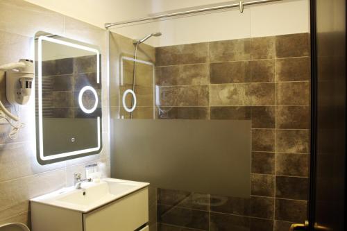 a bathroom with a sink and a shower with a mirror at Pensiunea Romeo Resort in Focşani