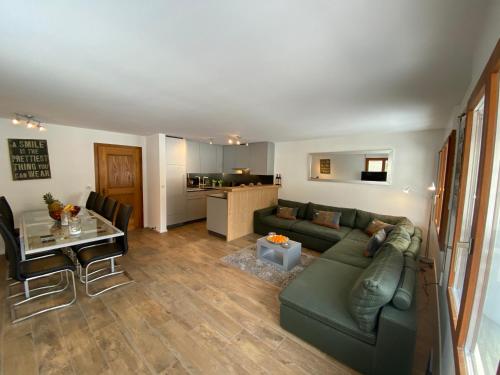 a living room with a green couch and a table at Casa al Lag - direkt am Laaxersee in Laax