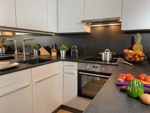 a kitchen with white cabinets and fruits and vegetables on a counter at Casa al Lag - direkt am Laaxersee in Laax