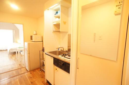 a small kitchen with a sink and a refrigerator at Plusone Nishikoen in Fukuoka