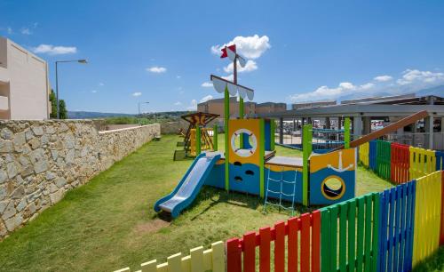 a colorful playground with a slide and a fence at Kiani Beach Resort Family All Inclusive in Kalyves