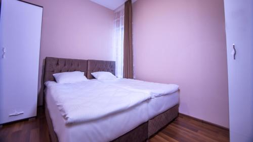 a bedroom with a bed with white sheets and a window at Wesoła Apartamenty in Wólka Kosowska