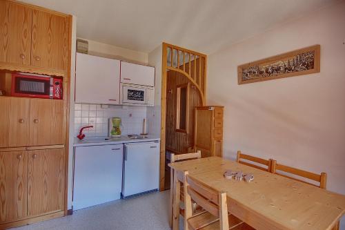 une cuisine avec une table en bois et un réfrigérateur blanc dans l'établissement APPARTEMENT PROCHE MORZINE CENTRE ET REMONTEES MECANIQUES - Orée de Morzine 24A, à Montriond