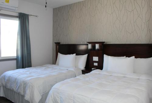 two beds sitting next to each other in a hotel room at Barefoot Caye Caulker Hotel in Caye Caulker