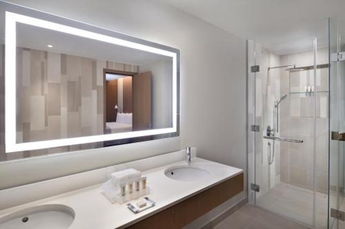 bagno con lavandino, doccia e specchio di Holiday Inn & Suites - Dubai Festival City Mall, an IHG Hotel a Dubai