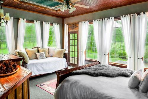 a bedroom with two beds and a couch and windows at Whimsical Gatehouse, Private Porch, Kitchenette in Franklin