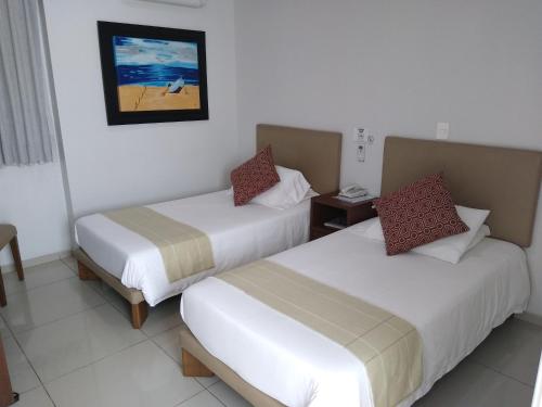a hotel room with two beds and a picture on the wall at Suites Chapultepec in Guadalajara