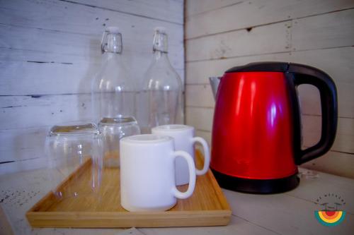 a wooden tray with two mugs and a red kettle at The Weekend Langkawi in Pantai Cenang