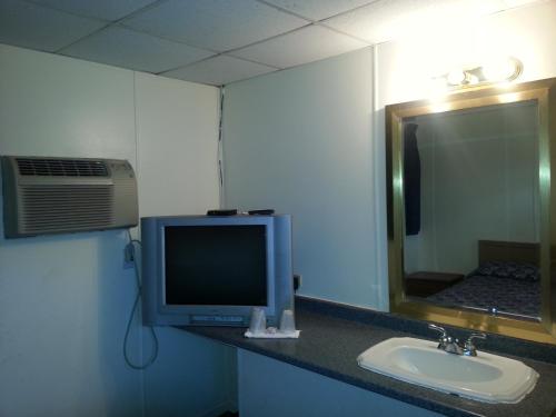 łazienka z telewizorem, umywalką i lustrem w obiekcie Americana Motel w mieście Avenel
