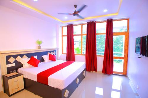 a bedroom with a bed with red curtains and a window at Cloudfoster Thekkady in Vandanmedu