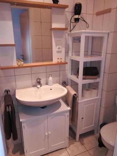 a white bathroom with a sink and a mirror at Haus Neunaber in Norderney
