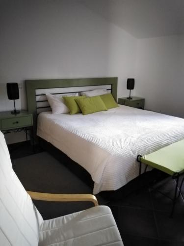 a bedroom with a large white bed with green pillows at Quinta de São João in Poios