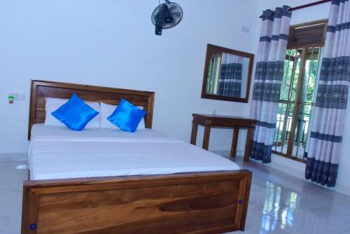 a bedroom with a bed with blue pillows at Wild Heaven Udawalawe in Udawalawe