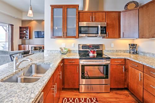a kitchen with stainless steel appliances and wooden cabinets at Breezy Lake Chelan Condo with Pool and Hot Tub Access! in Manson