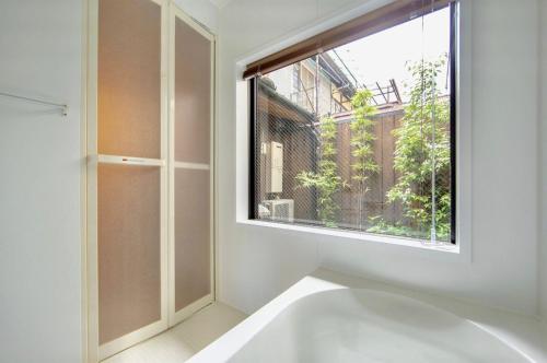 ein Bad mit einem Fenster und einer Badewanne in der Unterkunft Tsurui Nijo 鶴居二条 in Kyoto