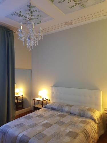 sypialnia z dużym łóżkiem i żyrandolem w obiekcie Appartamento Rosalba w Asti