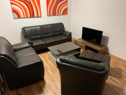 a living room with black leather furniture and a television at Heinsberg City in Heinsberg