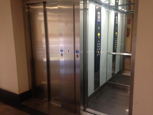 an elevator with glass doors in a building at Apartamentos Noluna in Segovia