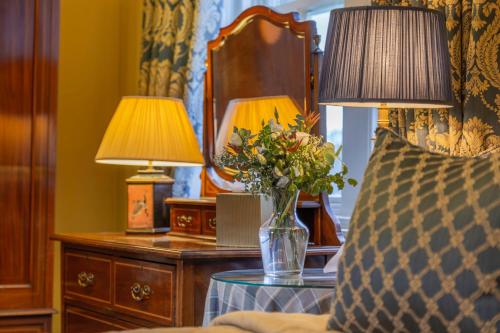 a bedroom with two lamps and a vase of flowers on a table at Glenapp Castle in Ballantrae