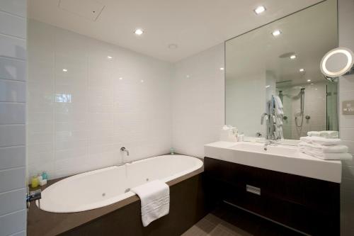 a bathroom with a tub and a sink and a mirror at The George in Christchurch