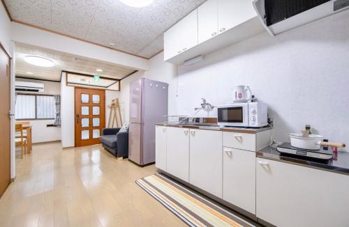 a kitchen with white cabinets and a microwave at Hiyori Nisijin 日和西陣 in Kyoto