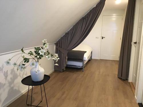 Habitación pequeña con cama y mesa con flores en Chez Marly en Oosterblokker