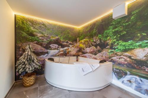 a bathtub in a bathroom with a painting on the wall at Serce Tatr Residence Zakopane - blisko Krupówek in Zakopane