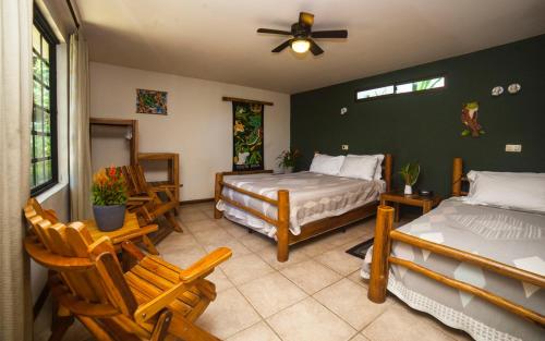 1 Schlafzimmer mit 2 Betten und Stühlen sowie einem Ventilator in der Unterkunft Pura Vida Hotel in Alajuela