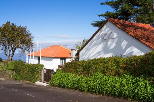 a white house with an orange roof on a street at Casas de Campo do Pomar B&B - Self Check-in in Santana